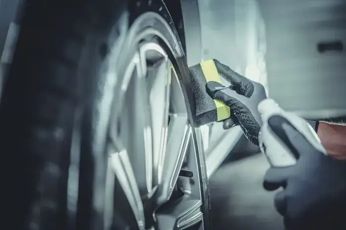 Detailer cleaning a vehicle wheel and rim with a foam applicator